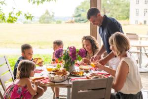 eine Familie, die am Tisch sitzt und Essen isst in der Unterkunft Domaine De La Boulaie in Treize-Vents