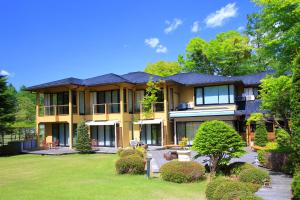 a large yellow house with a yard at Hatago Tsubakiya in Yamanakako