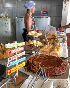 a woman standing in a kitchen with a buffet of food at Pousada America do Sol in Natal