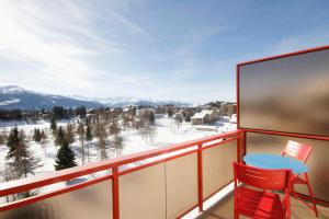 un balcón con mesa y sillas y montañas cubiertas de nieve en Hotel Elite, en Crans-Montana