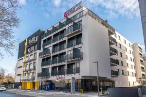 Un bâtiment blanc avec un panneau en haut dans l'établissement Focus Hotel Poznań, à Poznań