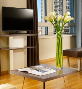 un jarrón de flores sobre una mesa en la sala de estar en UNAHOTELS Century Milano, en Milán