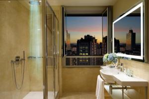 baño con ducha, lavabo y ventana en UNAHOTELS Century Milano, en Milán