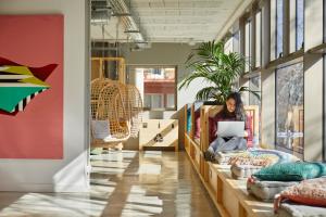 une femme assise sur une table dans une pièce avec un ordinateur portable dans l'établissement Unite Hostel Barcelona, à Barcelone