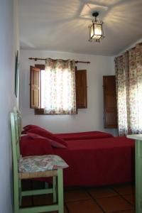 a bedroom with a red bed and a window at Hostal Rural Las Terrazas de la Alpujarra in Bubión