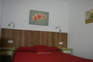 a bedroom with a red bed with two lights above it at Hostal Rural Las Terrazas de la Alpujarra in Bubión