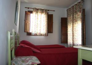 a bedroom with two red beds and a window at Hostal Rural Las Terrazas de la Alpujarra in Bubión