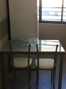 una mesa de cristal con 2 sillas y una mesa con platos. en Ria Apartments, en Olhão