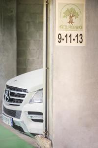 a white car is parked next to a hotel driveway at Hôtel Provence in Draguignan