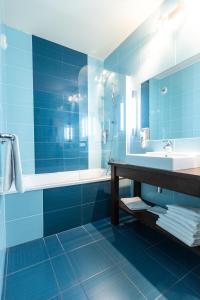 a blue bathroom with a tub and a sink at Hôtel Provence in Draguignan