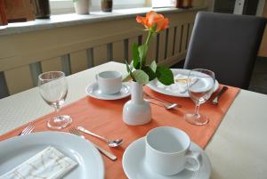 een tafel met borden en bekers en een vaas met een bloem bij Frühstückspension Paradiesgartl in Amstetten