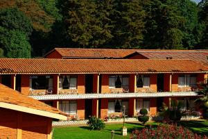 un edificio de ladrillo rojo con árboles en el fondo en Hotel Pie de la Sierra, en Uruapan del Progreso