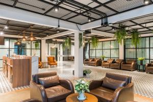 a lobby with leather chairs and tables and windows at Marwin Villa in Bangkok