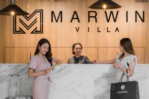 three women standing in front of a counter in front of a sign at Marwin Villa in Bangkok