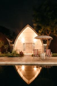 una casa con due sedie e un ombrellone accanto a una piscina di La Roja Bungalows a Nusa Penida