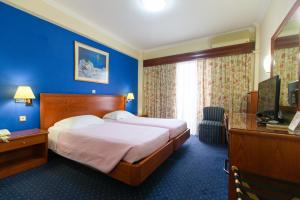 a hotel room with a bed and a blue wall at Grand Hotel in Larisa