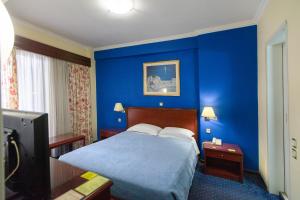 a blue bedroom with a bed and a tv at Grand Hotel in Larisa