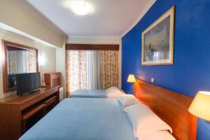 a hotel room with two beds and a television at Grand Hotel in Larisa