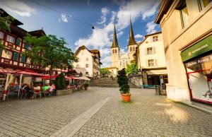 una calle de la ciudad con mesas y sillas y una iglesia en Lucerne Lake View Apartments, en Lucerna