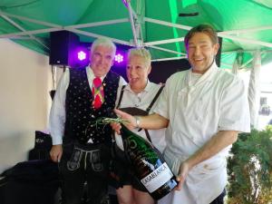 Zwei Männer und eine Frau mit einer Flasche Wein. in der Unterkunft Gasthof Toni in Kastelruth