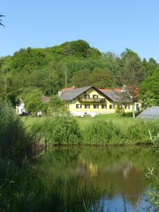 ein Haus auf einem Hügel neben einem Fluss in der Unterkunft Frühstückspension Krump in Bad Waltersdorf