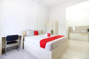 - une chambre blanche avec un lit et une chaise dans l'établissement Griya Izzara Guest House Syariah, à Sleman