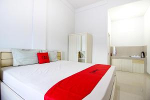 - un lit blanc avec une couverture rouge dans l'établissement Griya Izzara Guest House Syariah, à Sleman