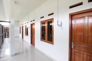 - un couloir avec des portes en bois et des murs blancs dans l'établissement Griya Izzara Guest House Syariah, à Sleman