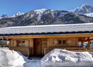 夏蒙尼-勃朗峰Chalets Ile des Barrats的雪中小木屋,背景是群山