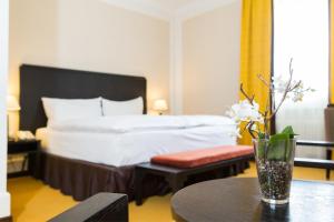 ein Hotelzimmer mit einem Bett und einer Vase aus Blumen auf dem Tisch in der Unterkunft Hotel Euler Basel in Basel