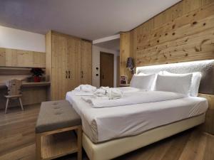 1 dormitorio con 1 cama blanca grande y pared de madera en Hotel Bertelli, en Madonna di Campiglio