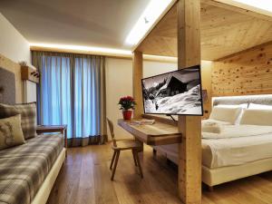 Habitación de hotel con cama, escritorio y sofá en Hotel Bertelli, en Madonna di Campiglio