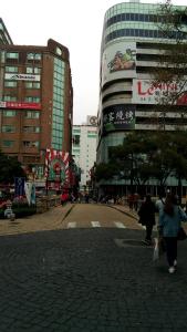 Un groupe de personnes marchant dans une rue avec des bâtiments dans l'établissement Persimmon Hotel, à Hsinchu