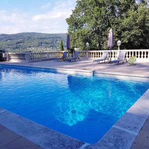 ein blauer Pool mit Stühlen und Sonnenschirmen in der Unterkunft Villa Manoe in Draguignan