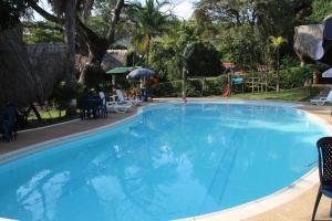 una grande piscina blu con sedie e ombrelloni di Eco Hotel El Reposo a Melgar