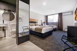 Habitación de hotel con cama y baño en CBD Motor Inn, en Coffs Harbour