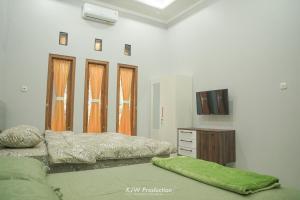 een slaapkamer met 2 bedden en een tv. bij M Stay Guest House Jogja in Yogyakarta