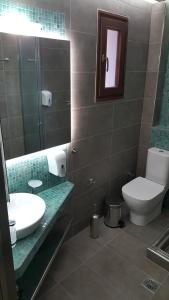 bagno con servizi igienici, lavandino e specchio di Antonia Apartments a Firà