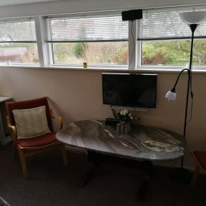 un salon avec une table, une télévision et une chaise dans l'établissement Risskov Bellevue Guesthouse, à Aarhus