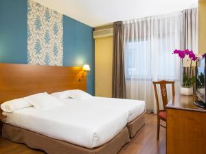 a hotel room with a large white bed and a desk at Oca Ipanema Hotel in Vigo