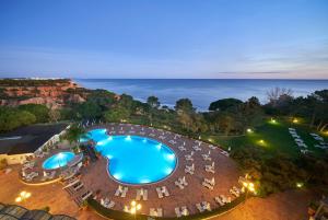 una vista aérea de una piscina con sillas y el océano en PortoBay Falesia, en Albufeira