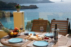 een tafel met wijnglazen en eten en uitzicht op de oceaan bij Barbara's House in Paleokastritsa