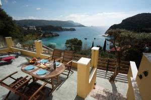 een balkon met een tafel en stoelen en uitzicht op de oceaan bij Barbara's House in Paleokastritsa