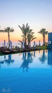 una grande piscina con palme e l'oceano di Blue Lagoon Kosher Hotel (by Capital Coast Resort & Spa) a Paphos