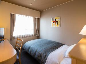 een hotelkamer met een bed, een bureau en een raam bij Himeji Castle Grandvrio Hotel in Himeji