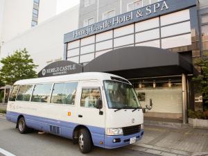 een witte en blauwe bus geparkeerd voor een gebouw bij Himeji Castle Grandvrio Hotel in Himeji