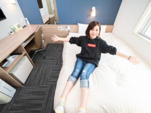 una chica sentada en una cama en una habitación en Super Hotel Towada Natural Hot Springs, en Towada