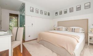 een witte slaapkamer met een groot bed en een stoel bij Cascais Casa Laranja in Cascais