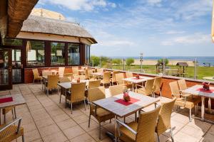 patio ze stołami i krzesłami oraz oceanem w obiekcie HAFFHUS - Hotel & Spa w mieście Ueckermünde