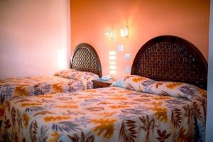 - 2 lits dans une chambre aux murs orange dans l'établissement Hotel Los Girasoles, à Tepic